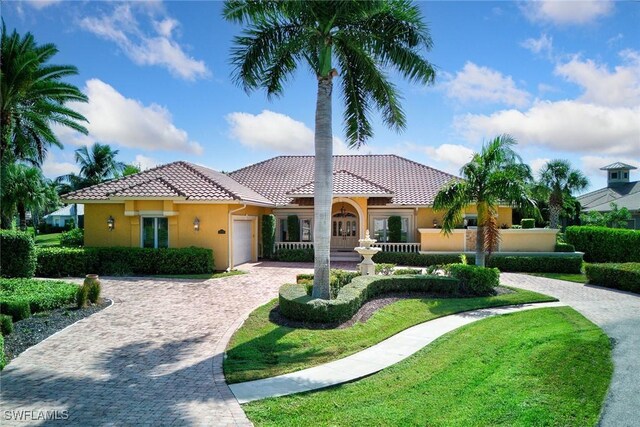 mediterranean / spanish-style home with a garage and a front lawn