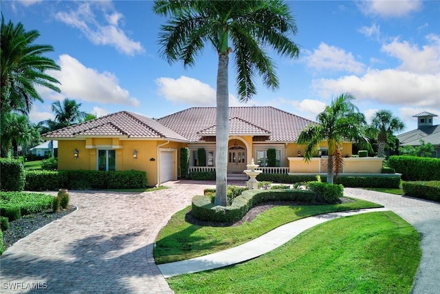 mediterranean / spanish-style home with decorative driveway, a garage, stucco siding, and a tiled roof