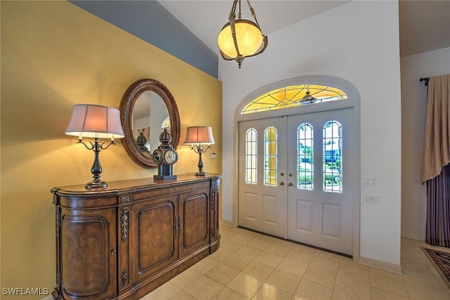 foyer with vaulted ceiling, light tile patterned floors, and baseboards