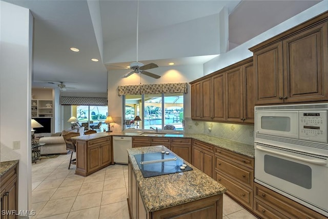 kitchen featuring backsplash, a center island, open floor plan, white appliances, and a sink