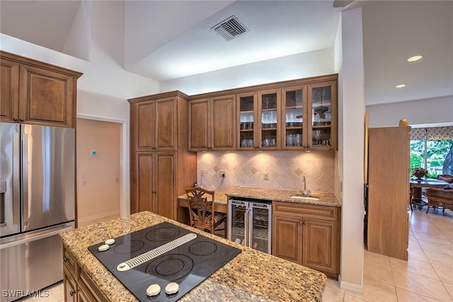 kitchen featuring visible vents, black electric stovetop, stainless steel fridge with ice dispenser, beverage cooler, and a sink