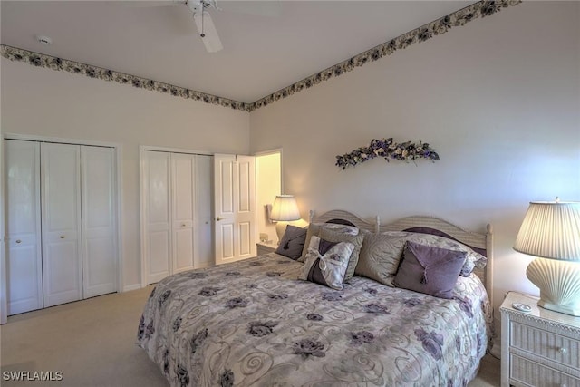 bedroom featuring light carpet, two closets, and a ceiling fan