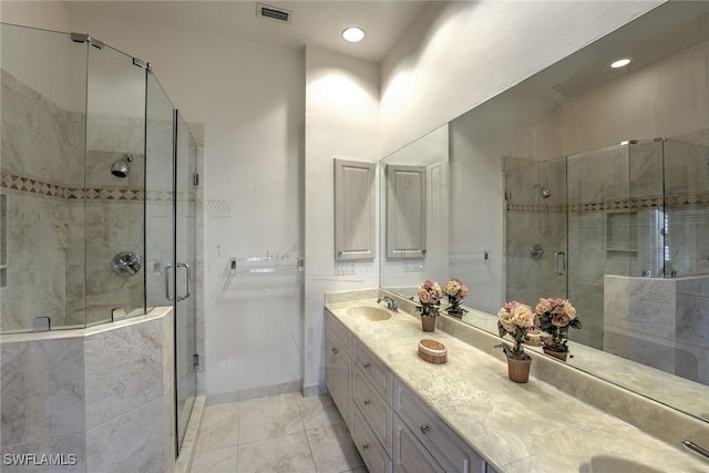 bathroom with visible vents, a shower stall, a sink, and double vanity