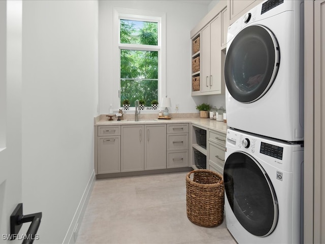 laundry room with cabinets, sink, and stacked washer and dryer