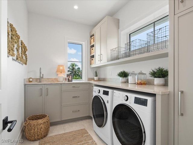 washroom featuring sink, light tile patterned floors, washing machine and dryer, and cabinets