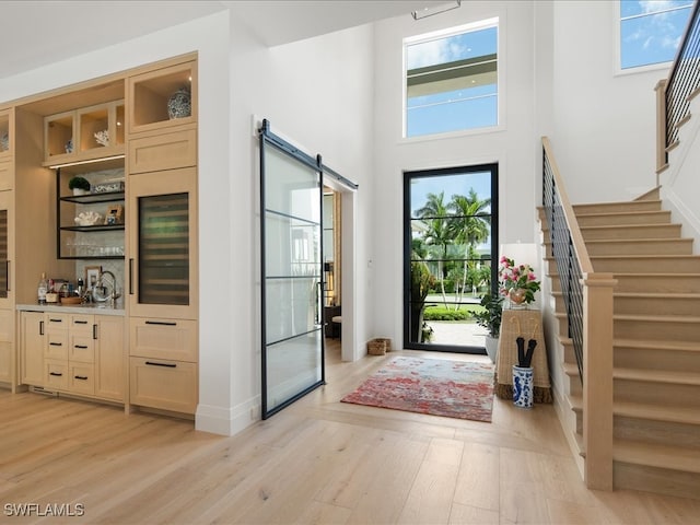 entrance foyer with a towering ceiling, a barn door, and light hardwood / wood-style flooring