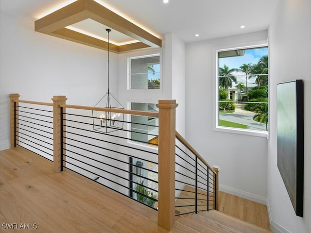 staircase with hardwood / wood-style floors and a chandelier