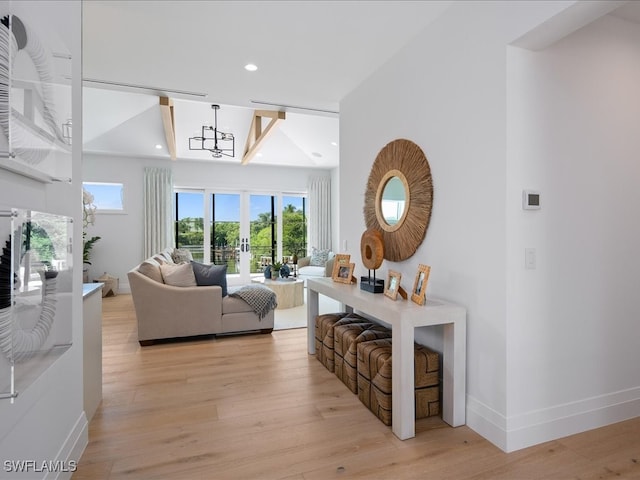 living room with lofted ceiling, a chandelier, and light hardwood / wood-style flooring