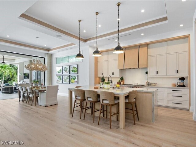 kitchen featuring a healthy amount of sunlight, a tray ceiling, a large island, and decorative light fixtures