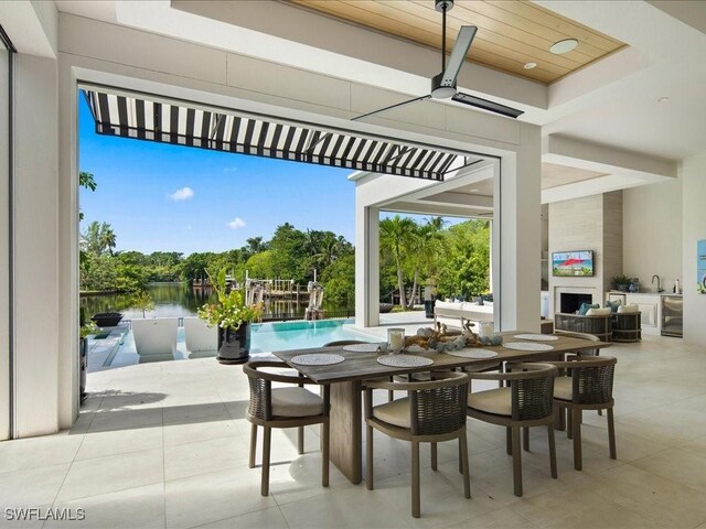 view of patio / terrace with exterior fireplace, sink, pool water feature, ceiling fan, and a water view