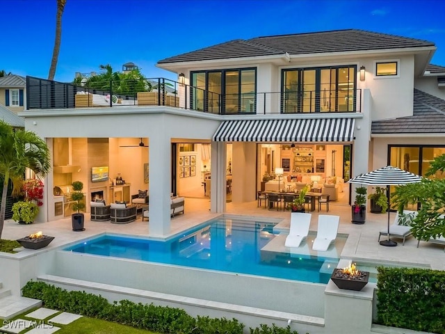 rear view of house with a patio area, an outdoor living space with a fire pit, and a balcony