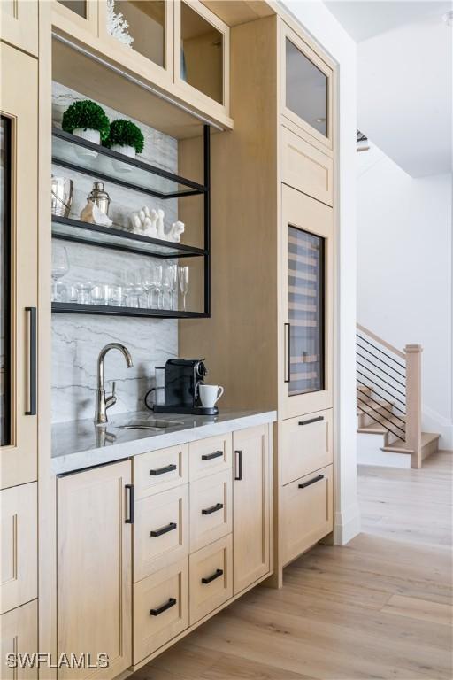 bar featuring wine cooler, light hardwood / wood-style floors, and sink