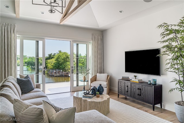 living room with french doors, vaulted ceiling, an inviting chandelier, and light hardwood / wood-style flooring