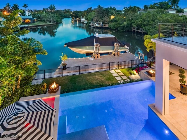 view of pool with a patio, a water view, a boat dock, and an outdoor fire pit