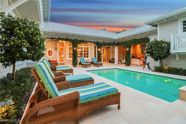 pool at dusk with outdoor lounge area and a patio area