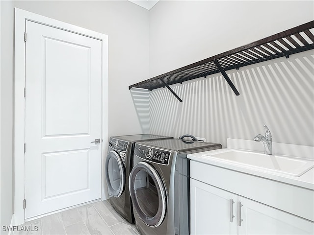 laundry area featuring separate washer and dryer, sink, and cabinets