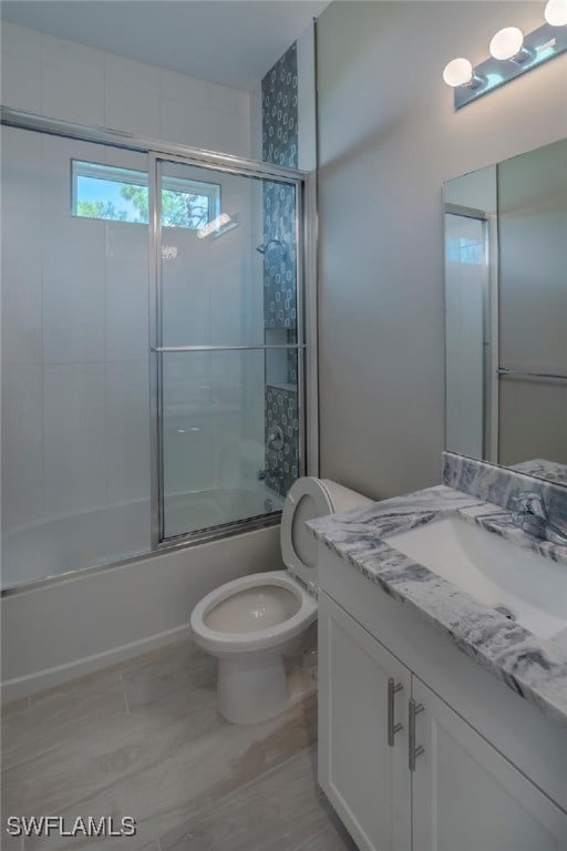 full bathroom with bath / shower combo with glass door, vanity, and toilet