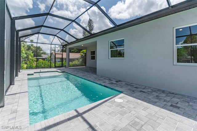 view of swimming pool featuring glass enclosure and a patio