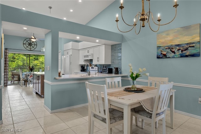 tiled dining room featuring sink, ceiling fan with notable chandelier, and a high ceiling