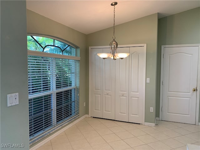 unfurnished dining area with light tile patterned floors and an inviting chandelier