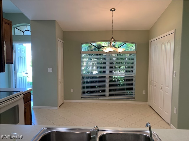 kitchen with white electric range, light tile patterned floors, sink, and hanging light fixtures