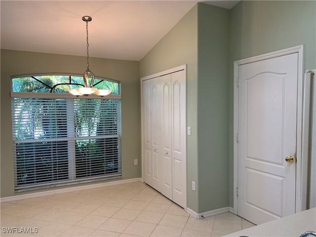 unfurnished dining area with light tile patterned floors and vaulted ceiling