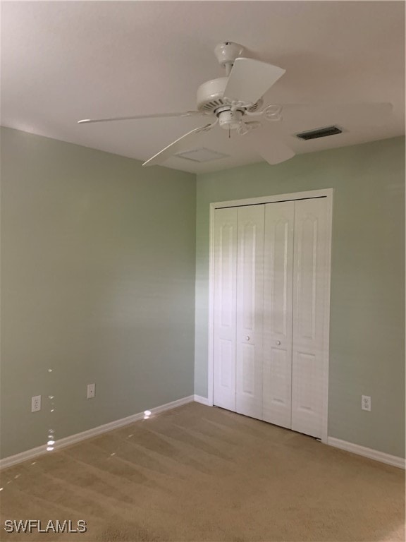 unfurnished bedroom featuring light colored carpet, ceiling fan, and a closet