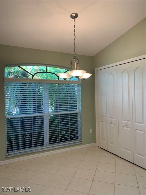 unfurnished dining area with lofted ceiling and light tile patterned flooring