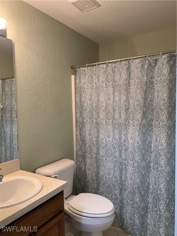 bathroom with vanity, toilet, and a textured ceiling