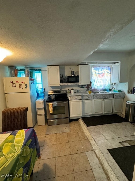 kitchen with stainless steel electric stove, white refrigerator, white cabinetry, and a textured ceiling