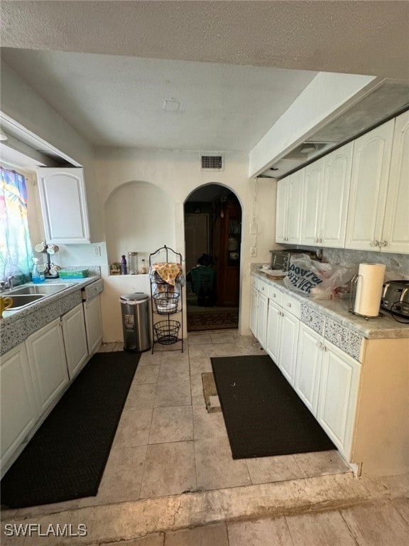 kitchen with white cabinets, sink, a textured ceiling, and tasteful backsplash