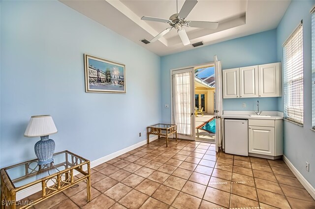 living area with sink, ceiling fan, a raised ceiling, and light tile patterned flooring