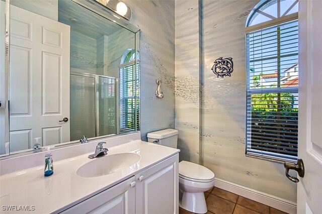 bathroom with vanity, toilet, tile patterned floors, and a shower with door