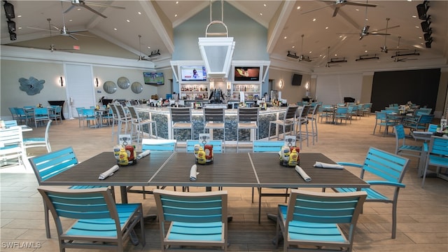 dining space with ceiling fan and high vaulted ceiling