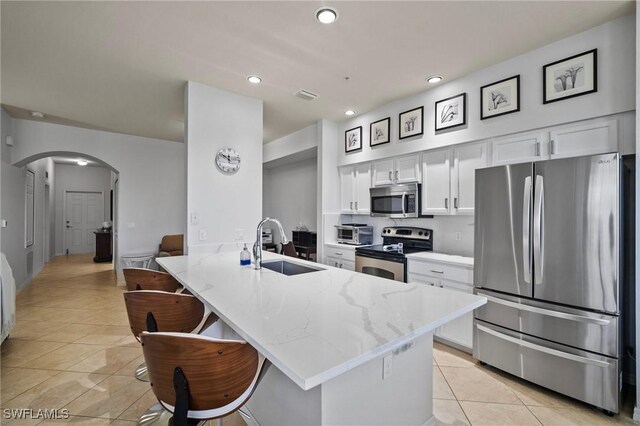 kitchen with appliances with stainless steel finishes, light stone countertops, white cabinets, sink, and kitchen peninsula