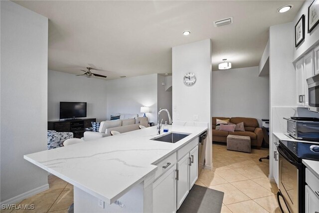 kitchen featuring sink, light stone counters, white cabinetry, stainless steel appliances, and kitchen peninsula