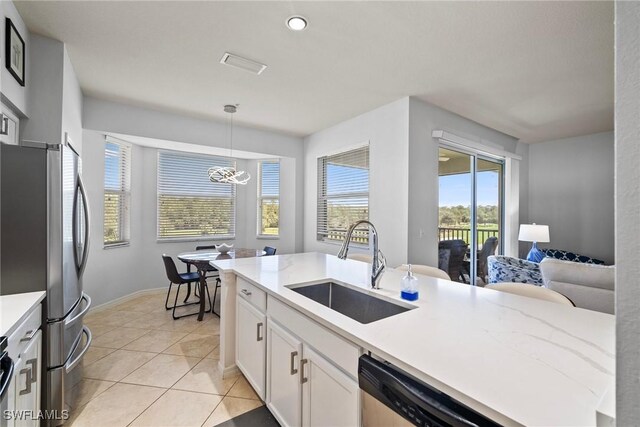 kitchen with hanging light fixtures, stainless steel appliances, sink, light tile patterned floors, and white cabinets