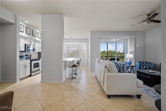 living room with ceiling fan, baseboards, and light tile patterned floors