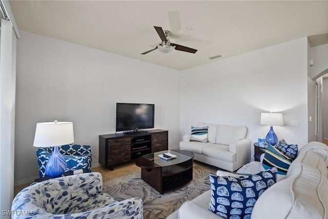 living room with baseboards, visible vents, and a ceiling fan