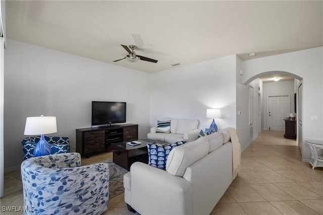 living room featuring arched walkways, light tile patterned floors, visible vents, ceiling fan, and baseboards