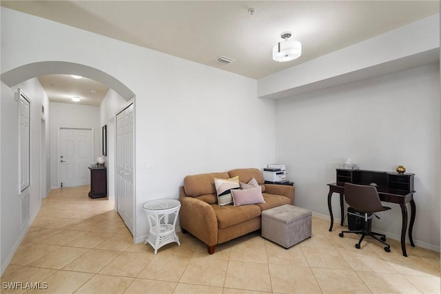 office area with light tile patterned floors, baseboards, visible vents, and arched walkways