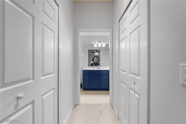 hall with a textured wall, light colored carpet, and a sink