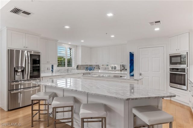 kitchen with a center island, stainless steel appliances, white cabinetry, and a breakfast bar area