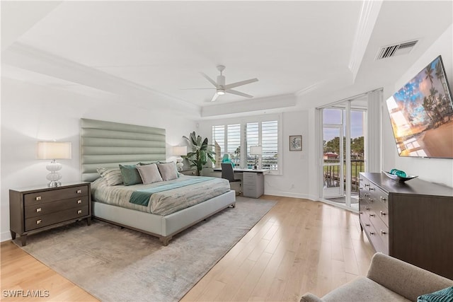 bedroom with light wood-type flooring, access to outside, ceiling fan, and a tray ceiling