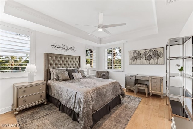 bedroom featuring a tray ceiling, ceiling fan, and light hardwood / wood-style floors