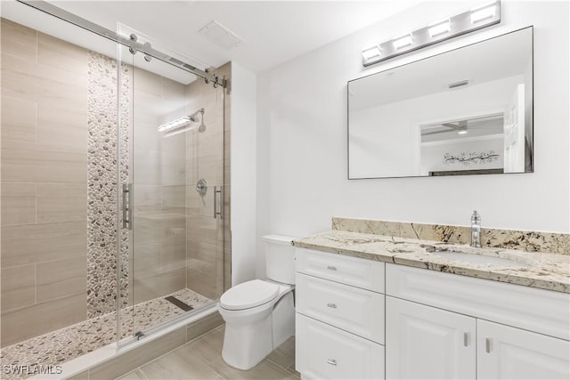 bathroom featuring vanity, toilet, and a shower with door