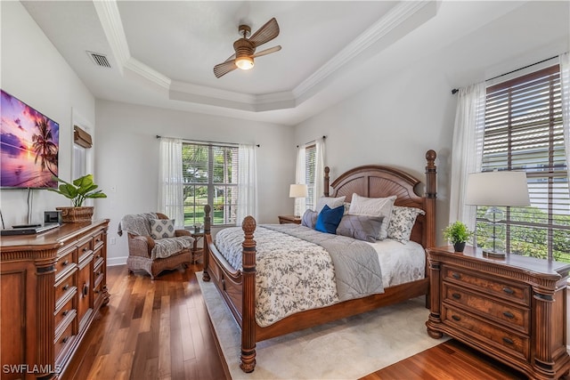 bedroom featuring ceiling fan, ornamental molding, a raised ceiling, and dark wood-type flooring