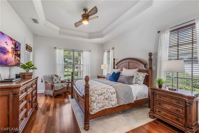 bedroom featuring crown molding, a tray ceiling, dark wood-type flooring, and ceiling fan