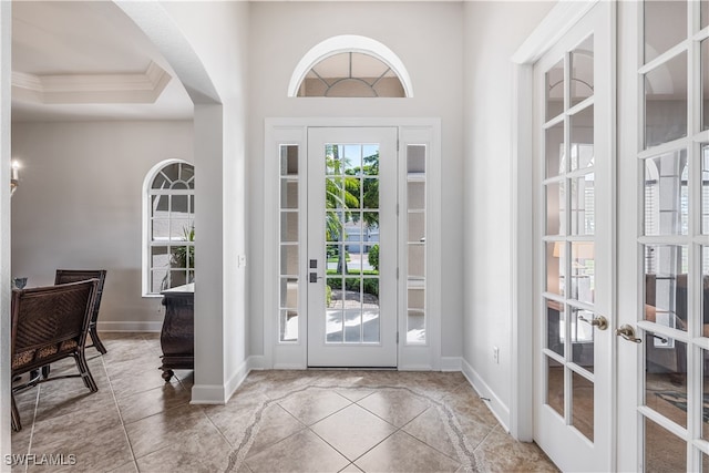 tiled entrance foyer featuring a raised ceiling, french doors, and crown molding