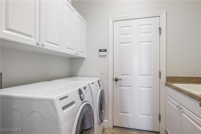 laundry room with washer and clothes dryer and cabinets